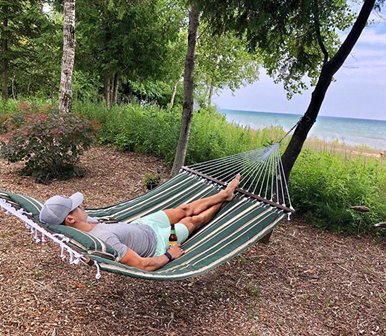 A person lying in a hammock at the lakefront