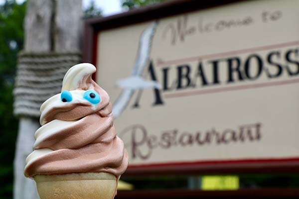 A chocolate-vanilla swirl cone with goofy eyes in front of the Albatross Restaurant sign.
