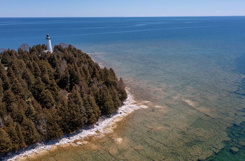 An aerial view of the Cana Island lighthouse and causeway on a sunny day.