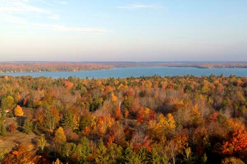 A sweeping aerial view of a forest in fall color leading to Clark Lake.