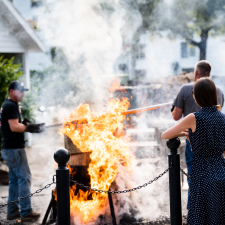 People standing around a large fire at a fishboil.