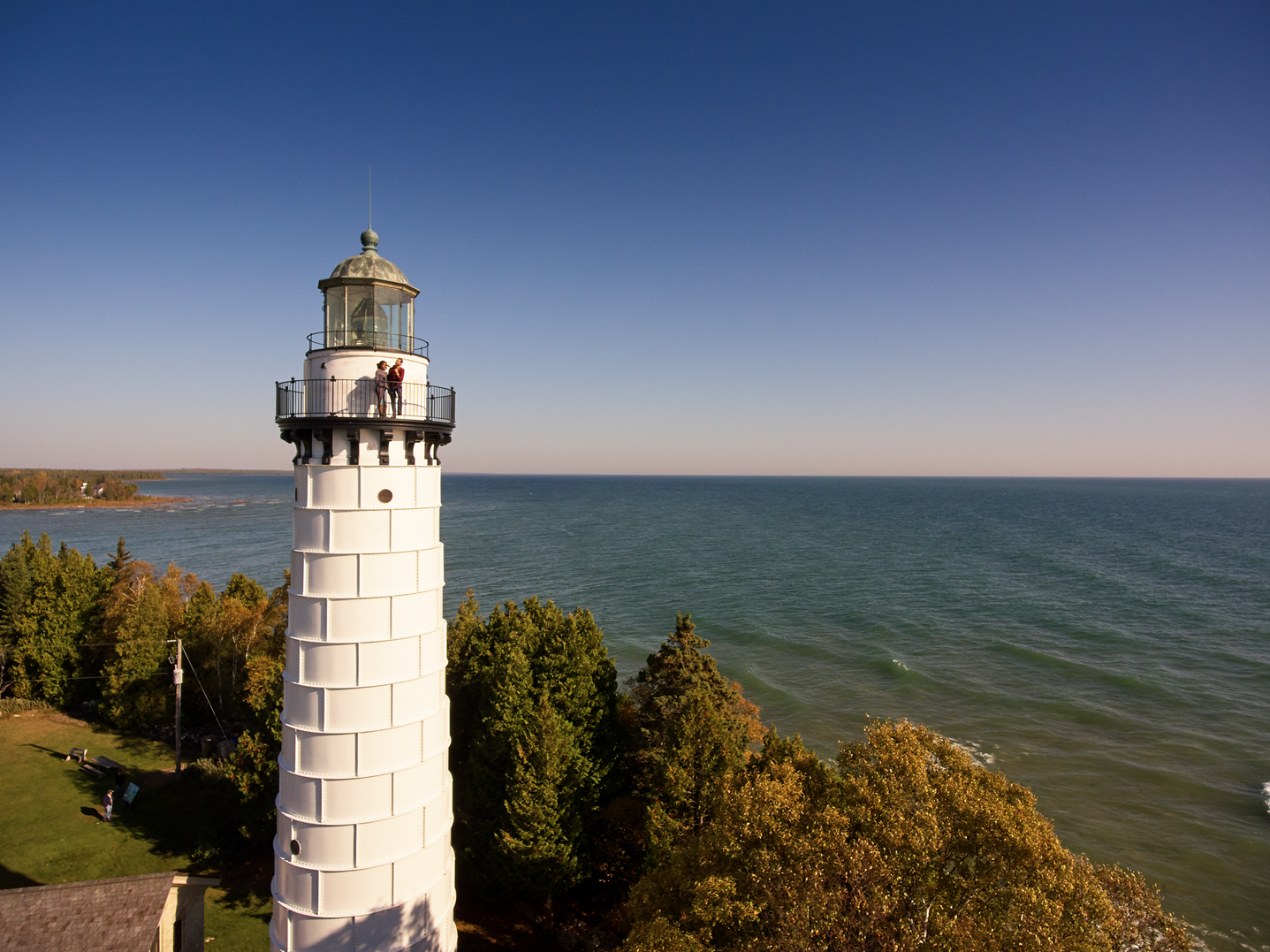 People stand on a balcony atop Cana Island lighthouse taking in the lake views.