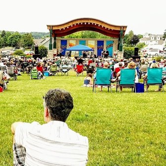 An audience in chairs on the lawn watching a show.