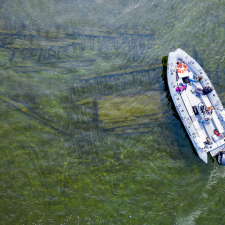 Aerial shot of a boat full of people over a shipwreck.