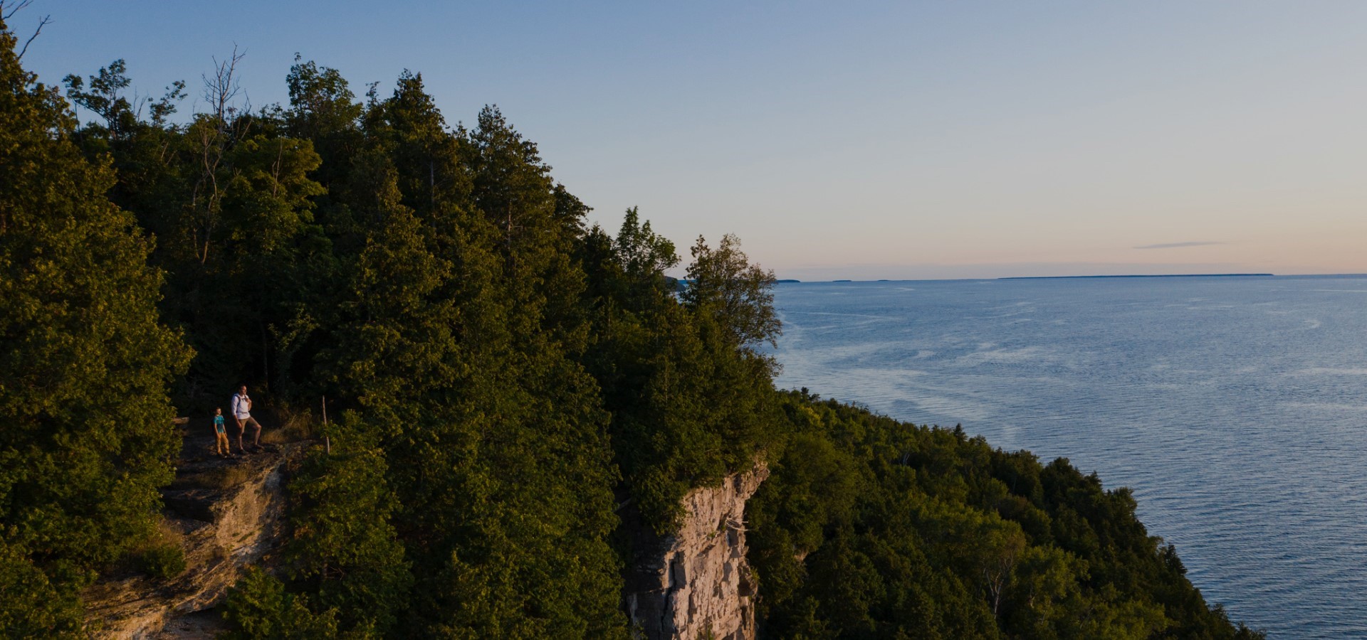 Trees along a cliff line with the lake in the distance.