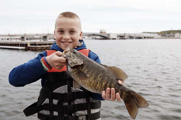 A young boy proudly shows off his catch.