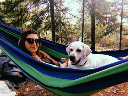 A woman with a dog in a hammock.
