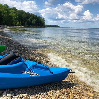 A blue kayak parked on the shore of the lake.
