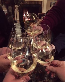 People toasting with glasses of white wine.