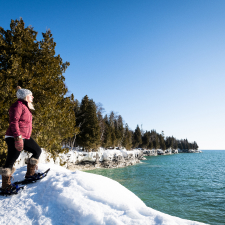A woman taking a break from snowshoeing to look at the lake