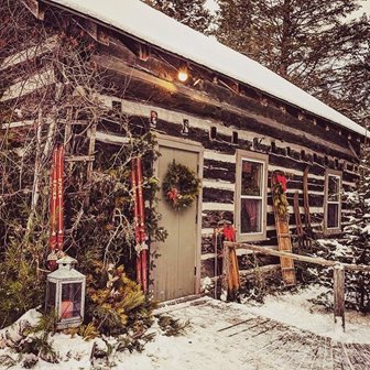 A snow-covered decorated cabin with a wreath
