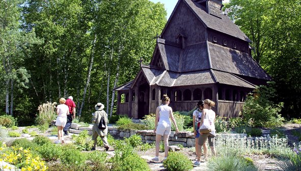 People walking towards a wooden building surrounded by trees.