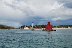 A red lighthouse on the lake at the end of a pier.