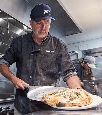 A chef transferring a pizza onto a pan