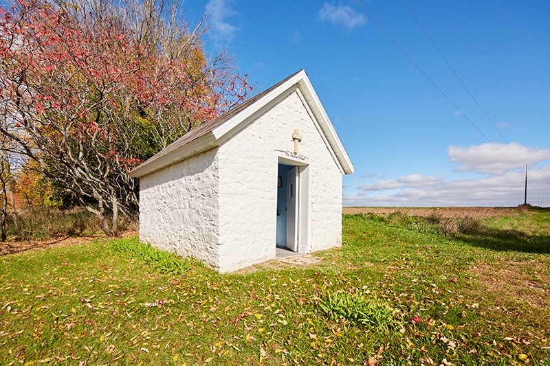 Small white stone chapel in a clearing.