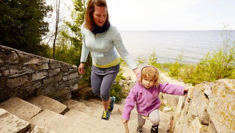 A woman walking up stone steps with her young daughter
