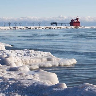 Ice-covered shoreline with a red lighthouse in the distance