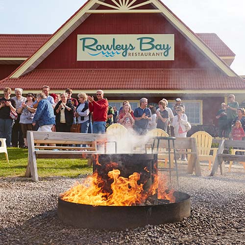 People outside of Rowley's Bay restaurant with a fire going.