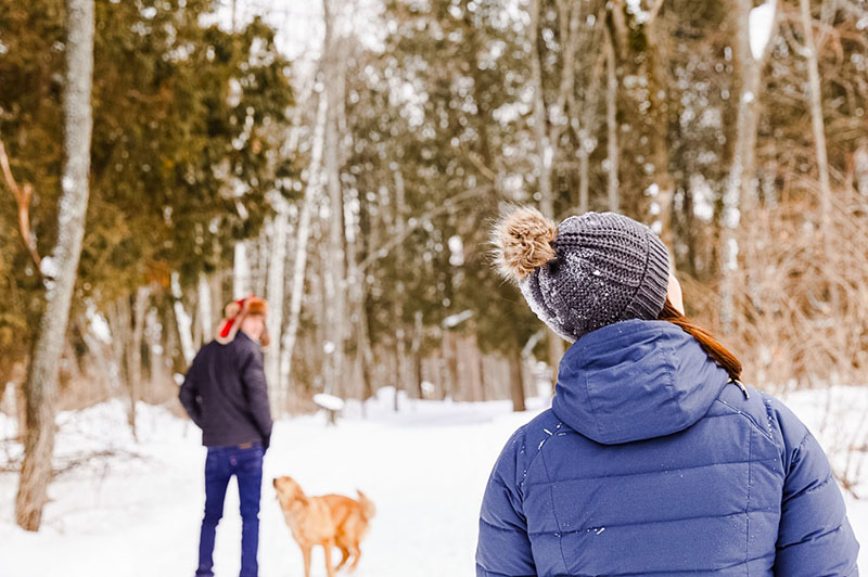 A couple and their dog hiking in a snowy trail