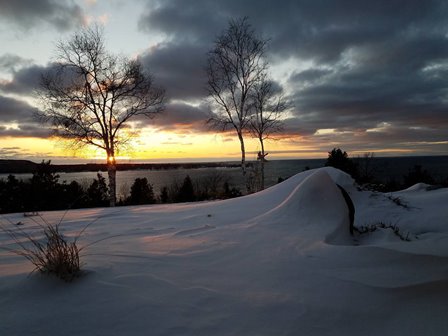 The sun setting over the snow and the lake.