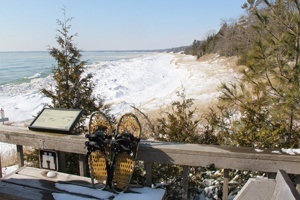 Snowshoes leaning against a fence with the snow-covered lake in the background.