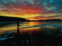 The silhouette of a person standing on the ice at sunrise.