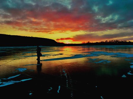 The silhouette of a person standing on the ice at sunrise.