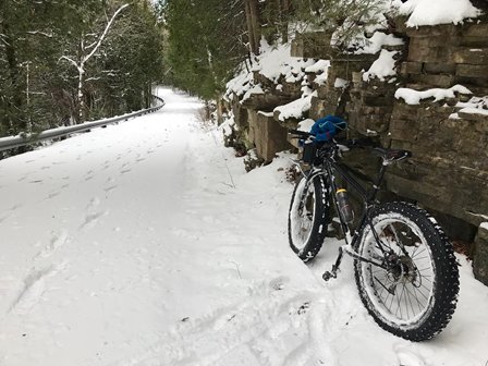 A mountain bike leaning against a stone wall in the snow