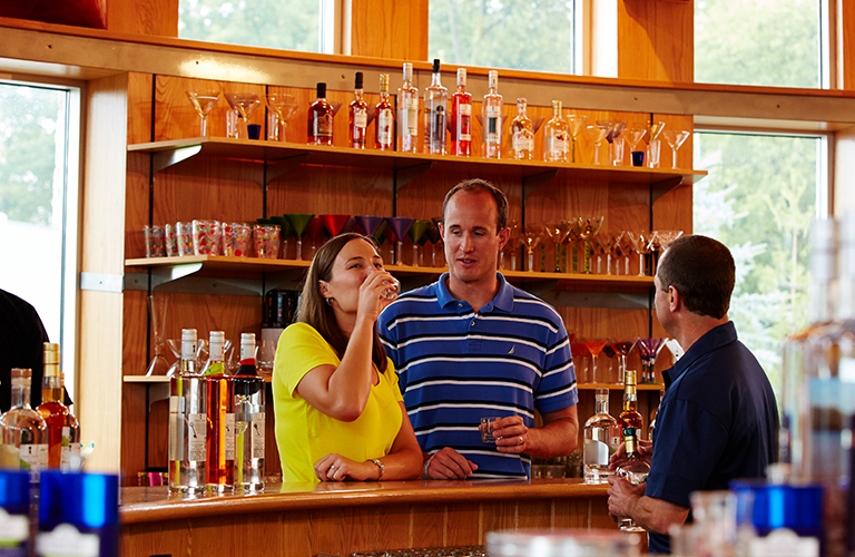 A couple sampling a glass of alcohol at a distillery.