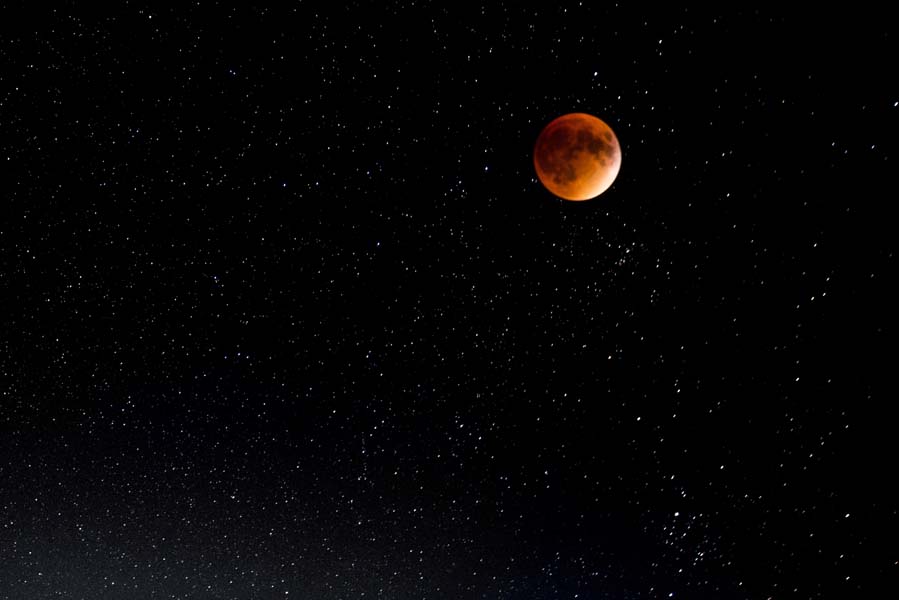 A glowing red moon hangs in a dark sky.