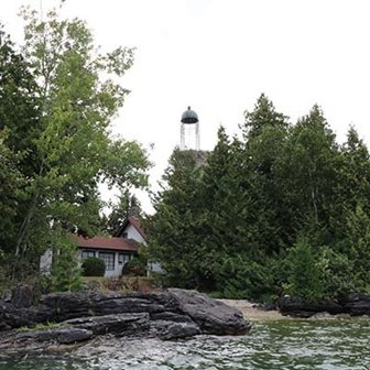 An old lighthouse surrounded by trees at the lakeshore.