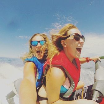 Two women laughing on a jet ski on the lake.