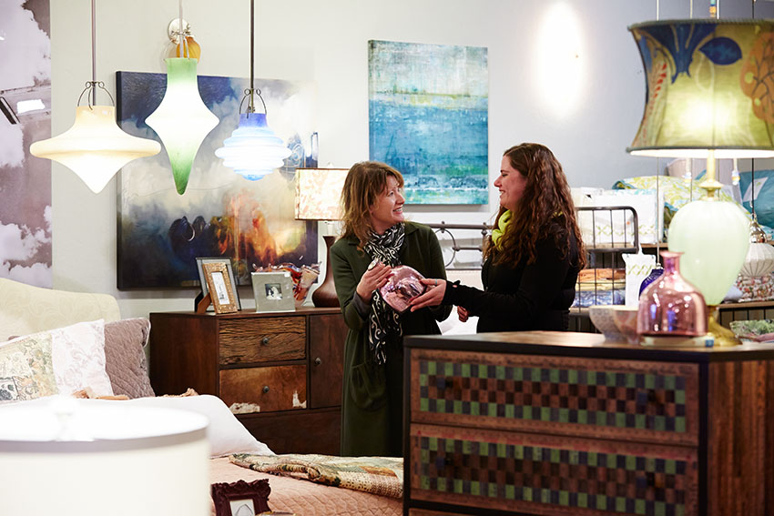 A shopkeeper and a customer discuss a piece of art in a gallery store.
