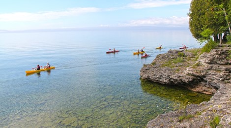 Seven kayakers paddling just offshore at the lakefront