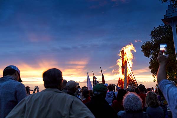 A groups watches a massive beach bonfire in awe at the Fyr Bal Festival.