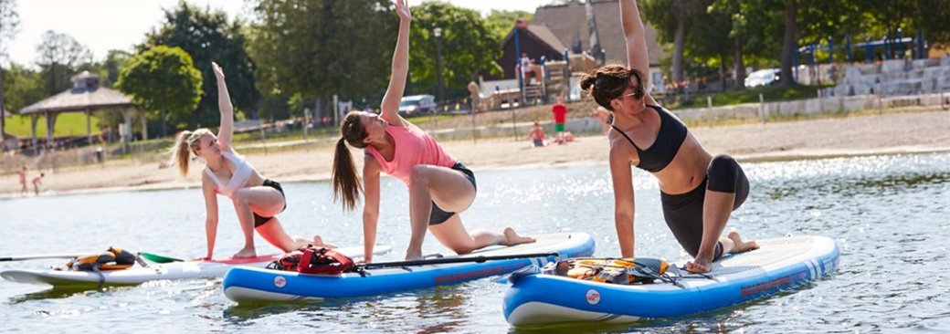 Three women doing yoga on paddleboards.
