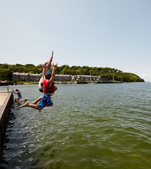 Children jumping off a dock into the lake.