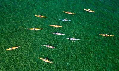 A large group visits Door County to kayak in crystal clear waters, just one of many popular activities after a destination meeting.