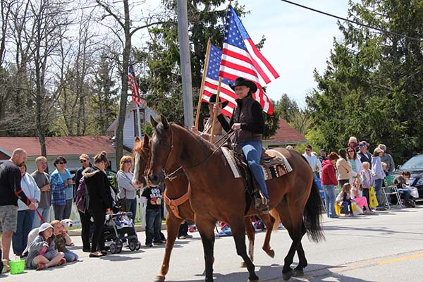 Men riding horses and holding American flags in a parade