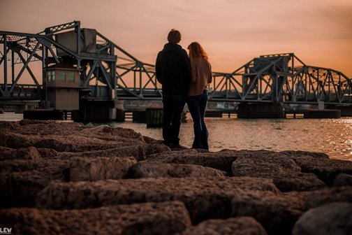A couple looking at a steel bridge at the lakefront