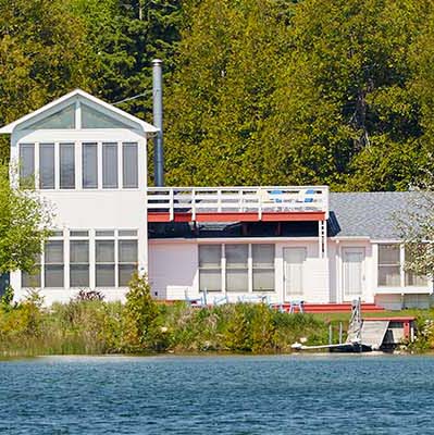 Three unique-looking rental cottages sit side by side on a crystal-blue shoreline.