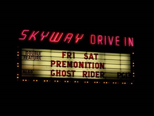 An old-fashioned movie theater marquee at Skyway Drive-In advertising the movies "Premonition" and "Ghost Rider."