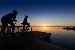 People biking by the lake at sunset