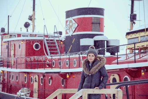 A woman in a winter coat and hat standing on a red boat