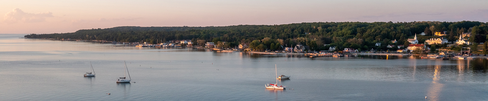 Door County hotels and lodges, ideal for large groups, sit alongside the shore as boats sail across the water.