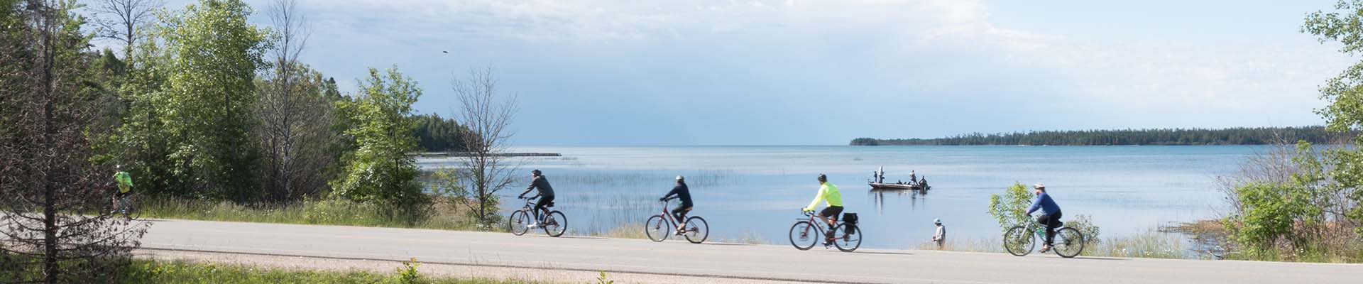 Distance shot of people riding bikes on a path along the lake