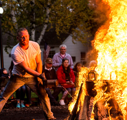 Person igniting and maintaining a fire at a fish boil.