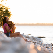 A woman hugging her dog by the lake