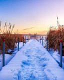 Foot prints in the snow on a boardwalk.