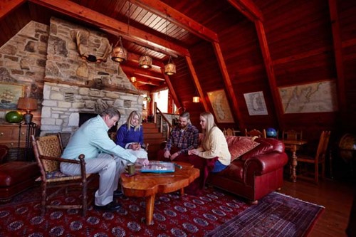 A family plays games in a cabin beside the fireplace.